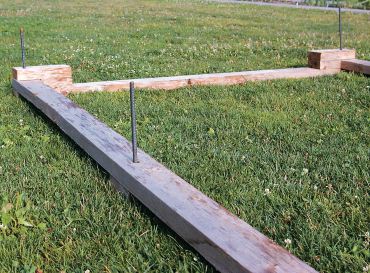 Step 5. Once the foundation boards slide together and are laid out as desired over the planting area, hammer 2-foot rebar stakes through holes to anchor firmly to the ground.