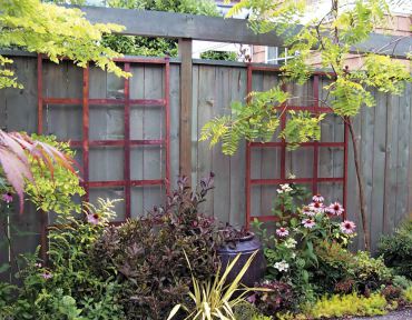 Make boring fences beautiful by adding artistry before surrounding it with plants. Hang vintage windows or use trellises as vertical accents. Create a "scene."