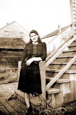 A 17-year-old Lorene Klamke strikes a pose for her boyfriend in front of her parents' Port Gamble home. Her parents lived on Skunk Hollow, which is now Teekalet Street, across the highway from the baseball field. Years after her family moved, the house was badly damaged in a fire and was torn down.