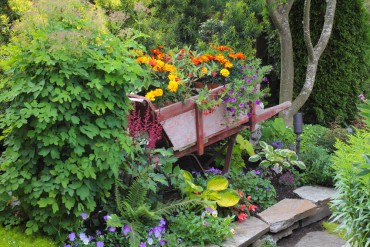 A wooden wheelbarrow — planted with colorful annuals and tender plants — came to live in their garden after Rudell and her brother saw a wooden one during a garden tour. Her brother found one for her online at craigslist.