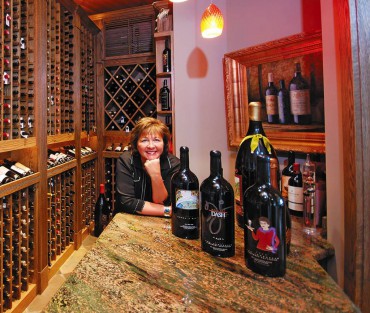 Moore, in one of her two wine cellars, displays four of her nearly 100 custom-etched and hand-painted wine bottles from Fresh Northwest Design in Gig Harbor.