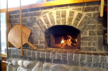 A small warming fire can be seen through the oven door of the Fortners' oven. To the left is a "peel," used to put loaves in and out of a hot oven.