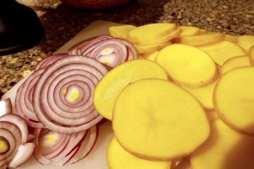 Sliced Yukon gold potatoes and a red onion