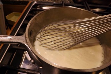 Bubbling white sauce ready for oven-baked scalloped potatoes