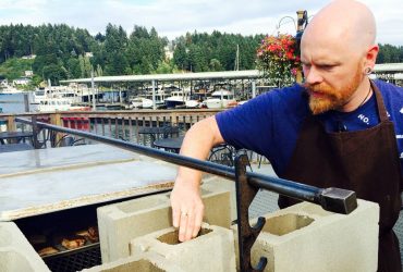 Chef Thad Lyman from Brix 25º builds up the coals on the outdoor grill for the pork belly course.