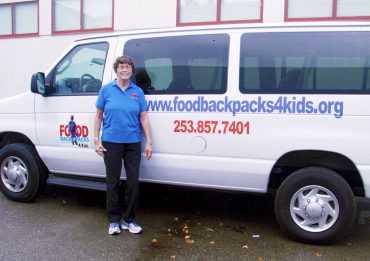 Karen Jorgenson, one of the founders of Food Backpacks 4 Kids, with the van obtained with help from Bruce Titus Ford in Port Orchard. The van is used to transport kids in the summer to the site of summer lunches. (Photo courtesy Hugh McMillan)