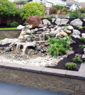 Terraced waterfall created with Columbia Granite Rockery and river rock installed by Full Throttle Landscaping