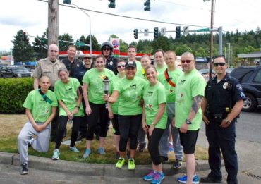 Runners and support personnel pause in East Bremerton during the Flame of Hope hand-off from the joint running team of the Kitsap County Sheriff's Office/Kitsap County Prosecuting Attorney's Office to Bremerton Police Department during the 2016 Law Enforcement Torch Run.