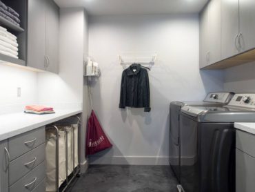 Storage is the primary focus of this second-floor laundry room — notice the catch pan peeking out under the washer.