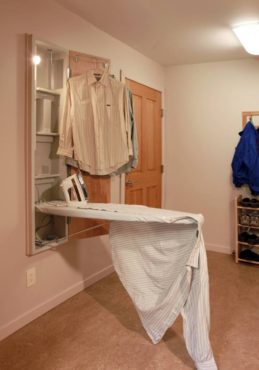 Combining laundry and mudroom amenities: built-in ironing board, coat rack and shoe rack