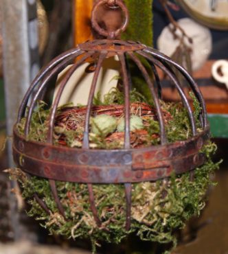 This rusty metal piece found at a vintage market inspires the use of ornate plant hangers or similar objects. Line it with moss to create a cozy space for the birds to find and build their nests.