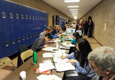 Judges scoring sheets and writing comments for students