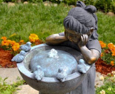 Birdbaths are always popular in a garden. This one adds a bubbling fountain for a bronze girl to gaze in fascination.