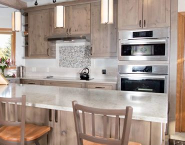 Steam oven (top) and wall oven with induction cooktop and awning-style ventilation hood (Photo courtesy A Kitchen That Works, LLC)