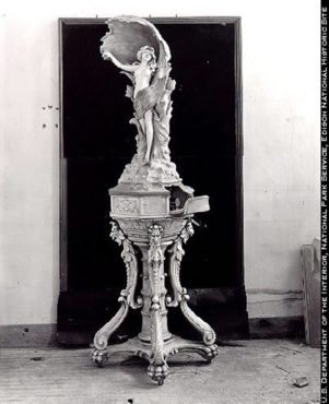 A phonograph cabinet built with Edison Portland Cement, 1912. The clockwork portion of the phonograph is concealed in the base beneath the statue; the amplifying horn is the shell behind the human figure. Today's version is the TV that can be disguised as art.