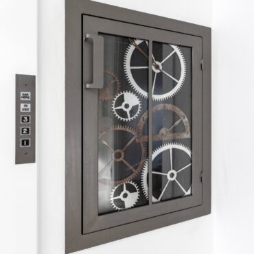 Dumb waiter, glass access doors mimic old elevator clockwork gears.