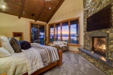 Cozy master bedroom with a Samsung TV mounted into the river-rock fireplace and custom-painted focal speakers in the ceiling
