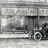 Jim Barnes' grandfather, Charles Goranflo, sits proudly on one of his agency'e Oldsmobiles. (Photo courtesy Barnes family)
