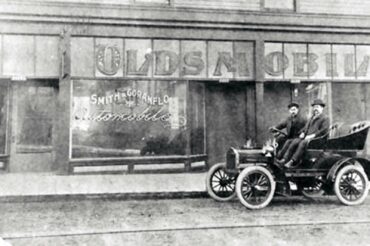 Jim Barnes' grandfather, Charles Goranflo, sits proudly on one of his agency'e Oldsmobiles. (Photo courtesy Barnes family)