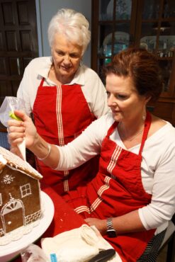 Author Barb Bourscheidt and daughter Cheryl Cavanagh decorate the gingerbread house.