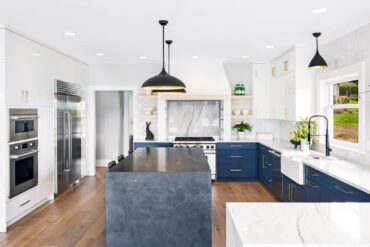 Kitchen featuring blue cabinetry and island and custom-designed hood (Photo courtesy Matthew Witschonke)