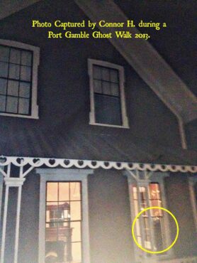 This photo, taken during a 2013 Ghost Walk at the house of former postmaster Daniel B. Jackson, caught an apparent apparition on camera. It shows what looks like a man in a suit standing in the window, but there was nobody inside the house. The photo was taken after the previous tenants had finished cleaning (and forgot to turn the light off), but before the new tenants arrived. Port Gamble town manager Pete Orbea said the building was empty at the time the photo was taken. (Photo captured by Connor H.)