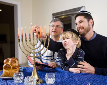 Three generations lighting a Chanukah menorah