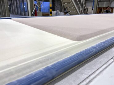 Stage 1 in the production of a porcelain slab — clay particles are deposited on a conveyor belt approximately 1.0625 inches in depth.