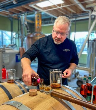 Bainbridge Organic Distillers owner and master distiller Keith Barnes pulling a barrel sample of his organic whiskey