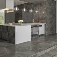 An example of the mineral drenching trend with walls, floor and island clad in the same large-format tiles in a glossy Nero finish from the Soberano by Vitromex USA