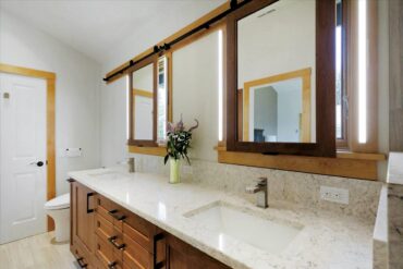 Twiggy LED bar lights mounted on either side of these vanity mirrors illuminate the person using the mirror (positioned over the window) when needed, then slide away when natural light is preferred.