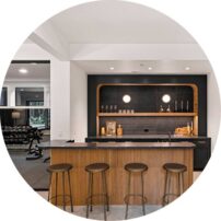 CHEERS The wet bar features Saratoga Quartzite counters with a leather finish, Z Collection tile walls, and wood walls by The Wood Veneer Hub.